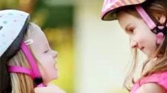 stock photo of young girl helping another with bicycle helmet